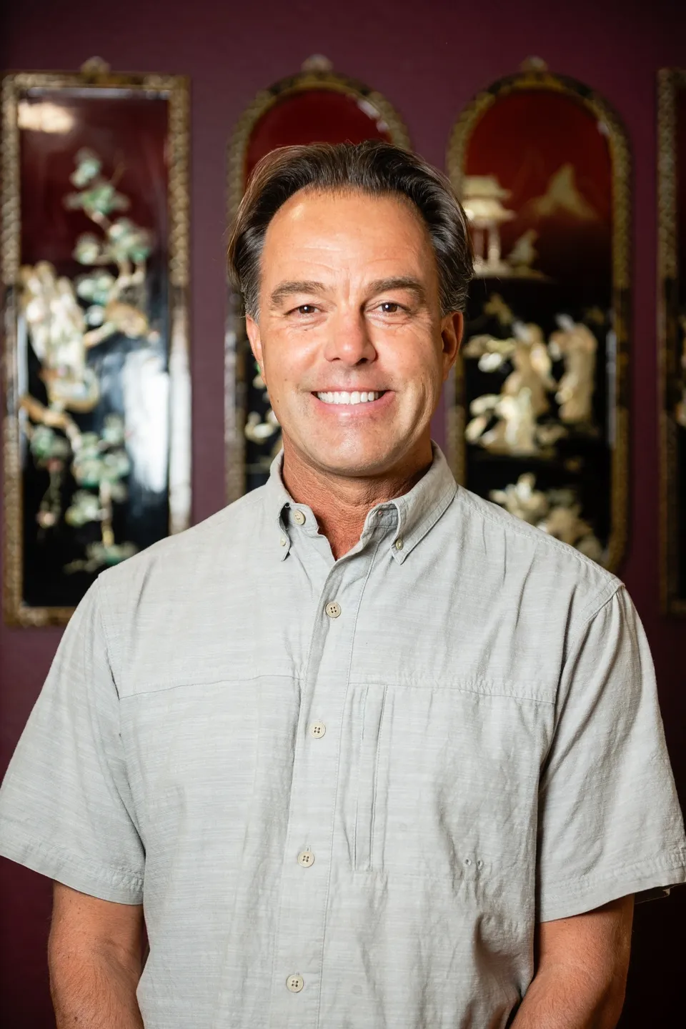 A man in grey shirt smiling for the camera.