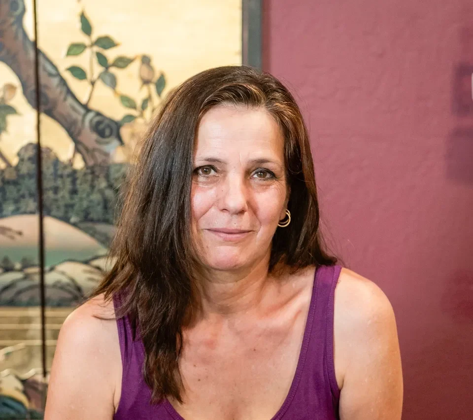 A woman in purple shirt sitting at a table.