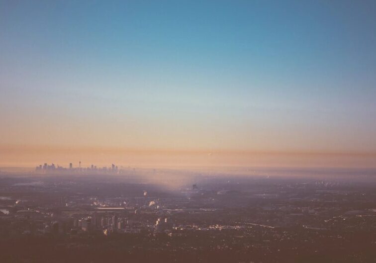 A hazy cityscape at dawn with soft pastel skies.